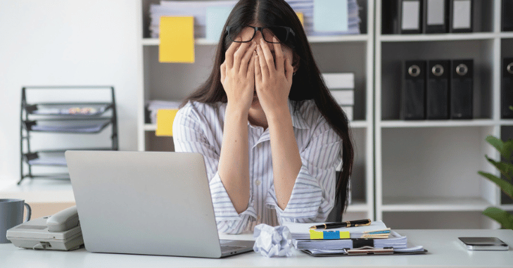 Adult sitting with head in hands feeling exhausted