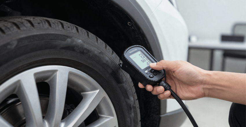 Driver checking tyre pressure on a driveway